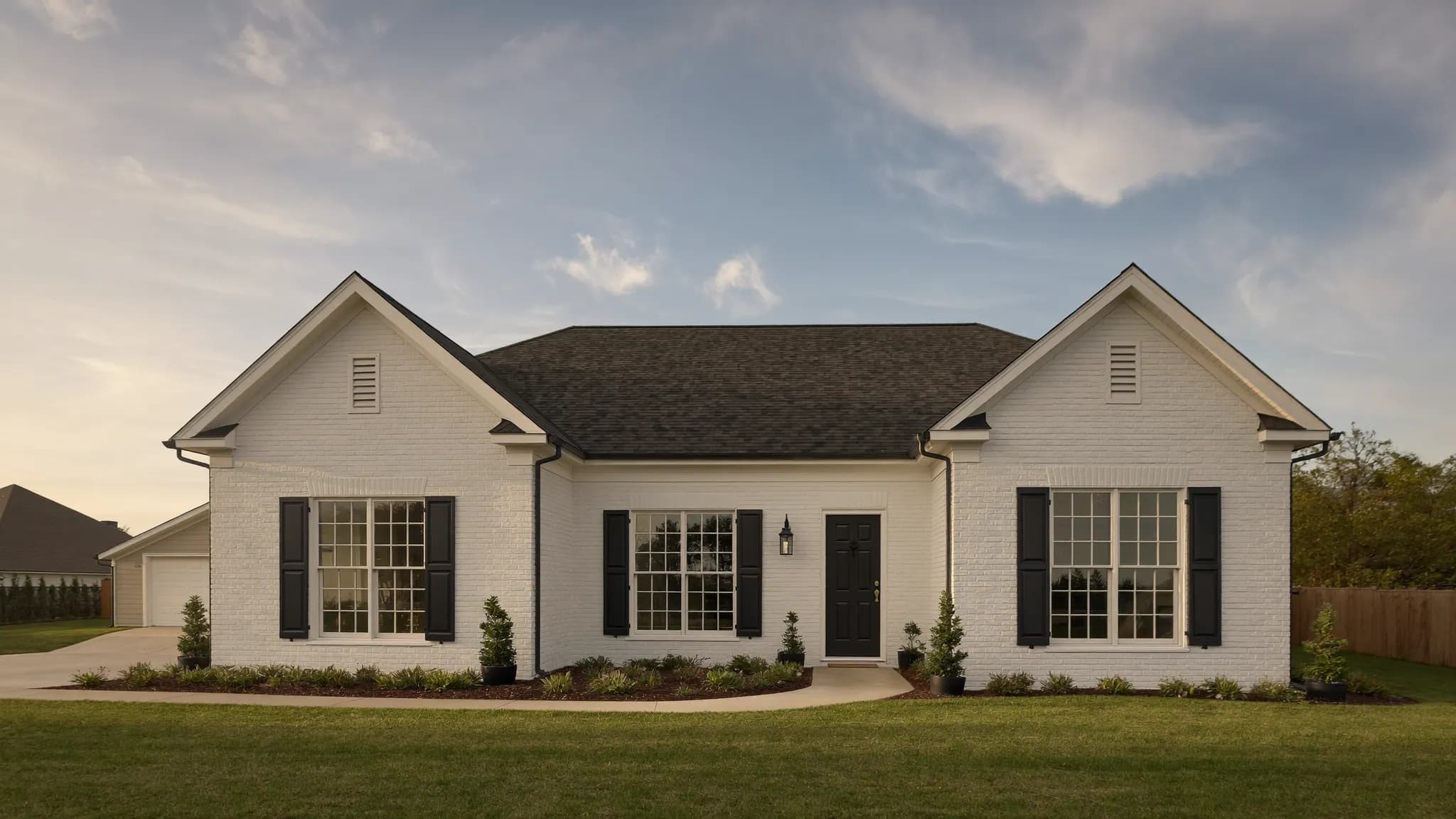 A newly built ranch home with a wide front porch in late afternoon light